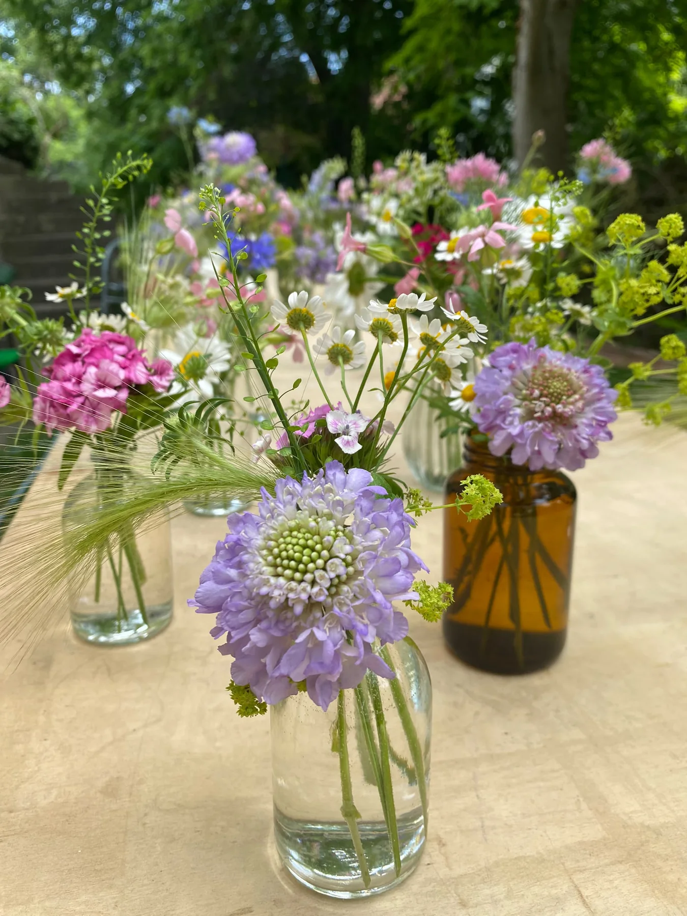 Kleine Glasvasen mit rosa, violetten und weißen Blüten