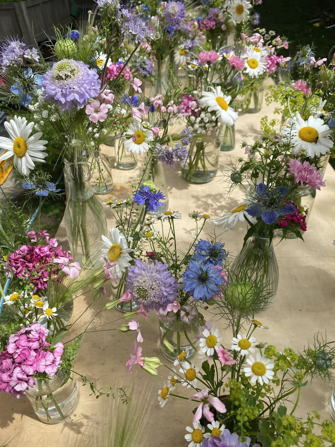 Teilnehmerinnen gestalten kleine Blumenvasen an einem langen Tisch